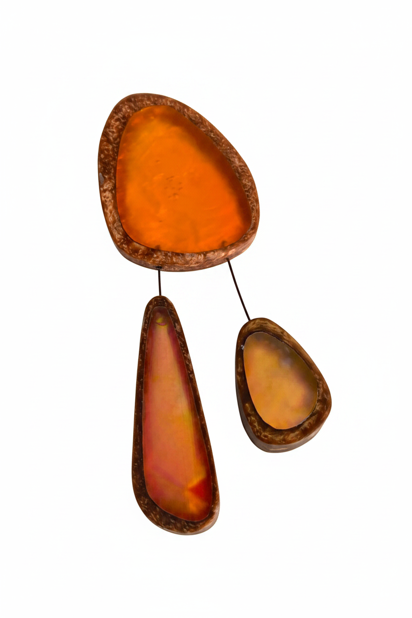 Broche XL en résine orange composée de trois éléments de différentes tailles,deux petits éléments sont reliés au plus grand par un cable rigide noir. fermeture aimant. broche posée sur fond blanc