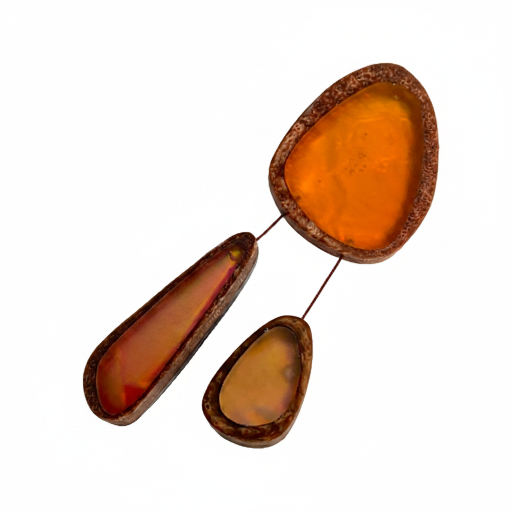 Broche en résine orange composée de trois éléments de différentes tailles,deux petits éléments sont reliés au plus grand par un cable rigide noir. fermeture aimant-fabrication-artisanale.
