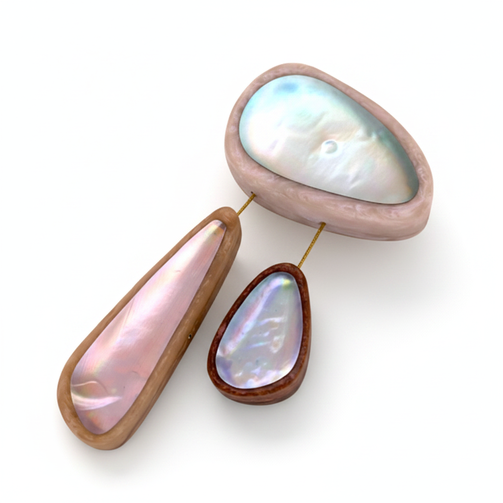 broche composée de 3 éléments de différentes tailles en résine couleurs pastel bleu clair,rose,bleu. les deux petits éléments sont reliés au grand par un cable rigide noir. fermeture aimant. broche posée sur fond blanc