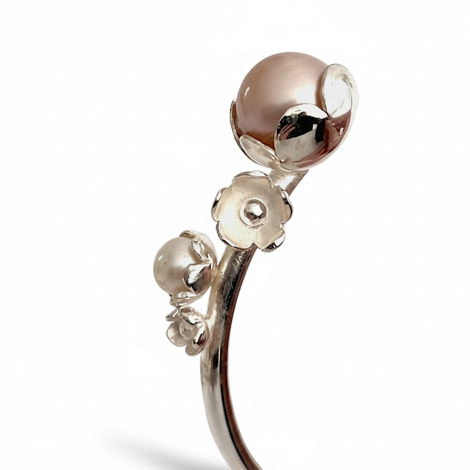 Bracelet jonc argent, orné de quatre motifs de fleurs et de trois perles de culture d'eau douce rose, grise, blanche. Une réalisation artisanale faite à la main inspirée par la nature.