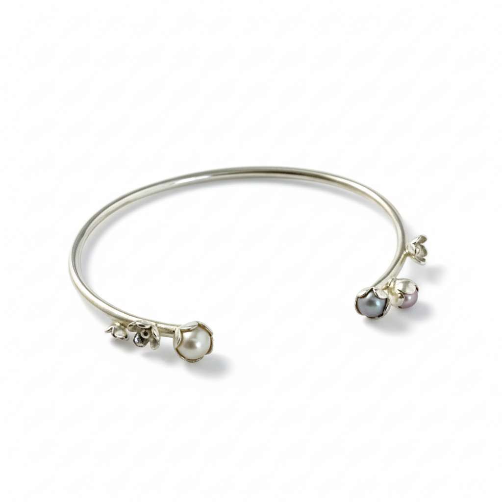 Bracelet jonc argent, orné de quatre motifs de fleurs et de trois perles de culture d'eau douce rose, grise, blanche. Inspirée par la nature cette pièce unique est faite à la main par la créatrice Patricia Lemaire.