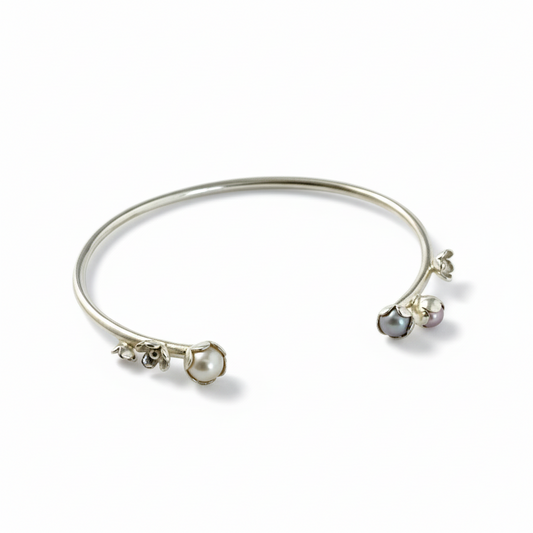 Bracelet jonc argent, orné de quatre motifs de fleurs et de trois perles de culture d'eau douce rose, grise, blanche. Inspirée par la nature cette pièce unique est faite à la main par la créatrice Patricia Lemaire.